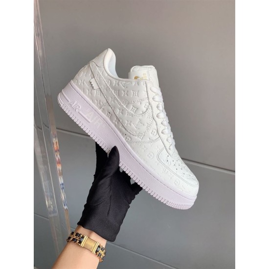Handheld View of L Air Force Embossed Monogram White Trainers Gloved hand holding white trainer showcasing side profile and sole