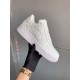 Handheld View of L Air Force Embossed Monogram White Trainers Gloved hand holding white trainer showcasing side profile and sole