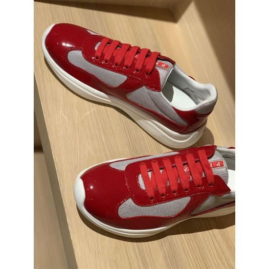 Angled view of Prada red patent leather and grey mesh trainers on display