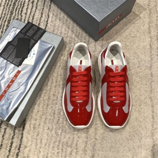 Top-down view of pair of Prada red and grey mesh trainers next to original shoe box