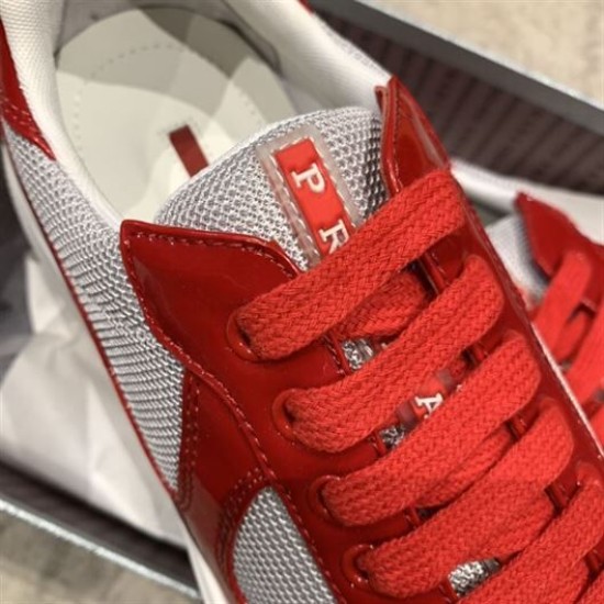 Close-up of red laces and Prada logo emblem on grey mesh tongue