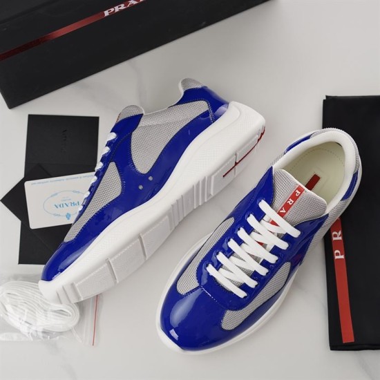 Prada America's Cup Trainers Accessories View in blue and grey Flat lay of Prada blue patent trainers alongside brand box and dust bag in blue and grey