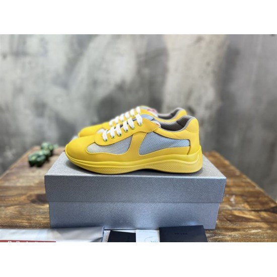Pair of yellow Prada trainers sitting on a silver box in yellow and grey