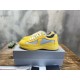 Pair of yellow Prada trainers sitting on a silver box in yellow and grey