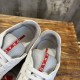 Close-up view of padded collar and red logo tab on tongue in white and grey