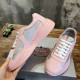 Hand holding a pink and grey trainer showing outer side rubber trim