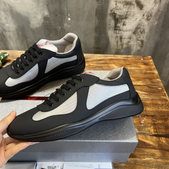 Lateral Profile Prada Trainer in black and grey Lateral side view of black and grey Prada trainer held above packaging