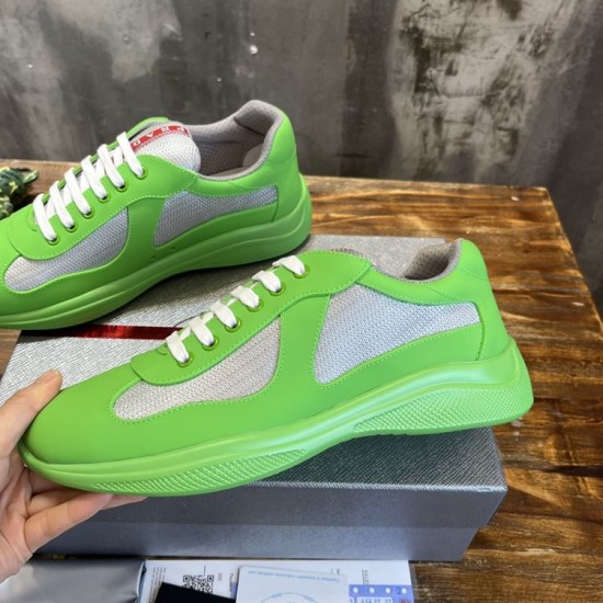 Hand holding a bright green trainer showing the lateral side and grey mesh panels