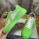 Side view of green rubber trainer rested on shoe box next to another shoe in green and grey