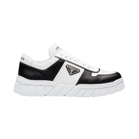 Prada Leather Low Top Trainers In Black And White - Side Profile Side profile of Prada leather low top trainers in black and white on studio background