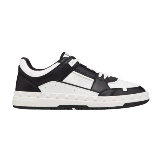 Side profile view of Valentino Freedots low-top leather trainers in black and white featuring studded midsole details.