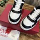 Close-up angled shot of the front leather panelling and lace closure on Valentino Freedots trainers in black and white.