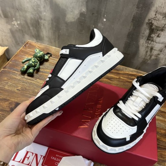 Handheld view showcasing the inner side wall and studded rubber sole of a black and white Valentino Freedots trainer.