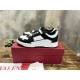 Three-quarter elevated shot of black and white Valentino Freedots trainers displayed on top of a red shoebox.