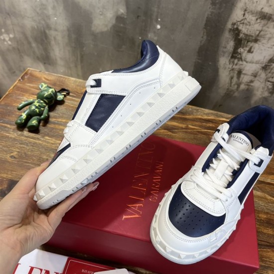 Hand holding up a Valentino trainer alongside another on a red shoe box in white and navy blue