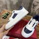 Hand holding up a Valentino trainer alongside another on a red shoe box in white and navy blue