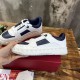 Hand holding a Valentino white and navy leather trainer showcasing side profile and rockstud trim in white and navy blue