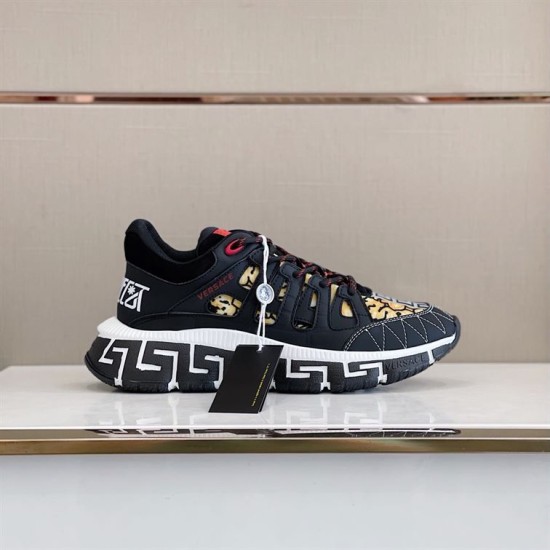 Profile view of black and gold Versace Trigreca footwear on display
