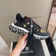 Handheld view of black and gold Versace Trigreca trainer