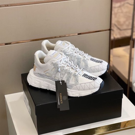 Versace Trigreca Trainers Angle View in white and gold Three-quarter elevated view of white Versace Trigreca leather trainers on black box in white and gold