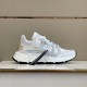 White Versace Trigreca Trainer Profile in white and gold Side view of white Versace Trigreca trainer with black tag resting on display shelf in white and gold