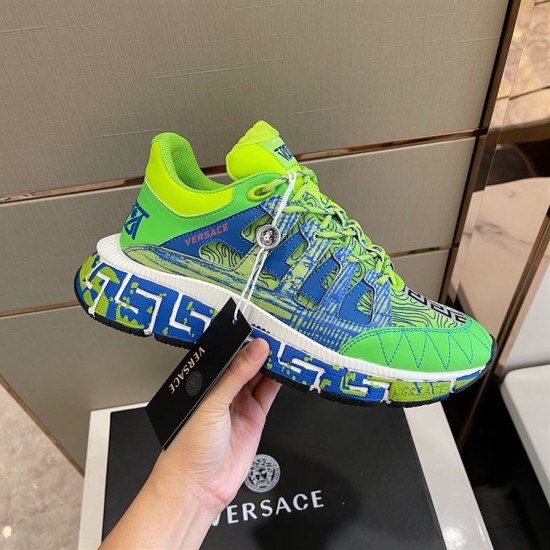 Hand holding the green and blue trainer showcasing side details and attached tags