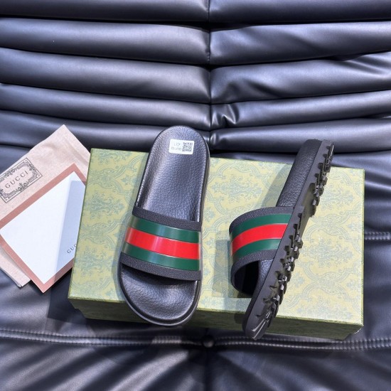 Gucci Slide Sandals Overhead View on Box in black and red Top-down view of black Gucci rubber slide sandals resting on a patterned green box alongside a dust bag in black and red