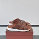 Pair of Loro Piana tabac brown ostrich leather slide sandals resting on a branded box