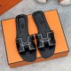 Top down view of Hermes black sandals resting on an orange box