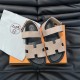 Hermes Suede Flat Sandals In Beige Flat Lay in beige and black Hermes beige suede sandals displayed on an orange box with a dust bag in beige and black