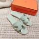 Hermes Oran Flat Sandals In Light Green - Top View with Box Top-down view of a pair of light green sandals displayed alongside an orange presentation box