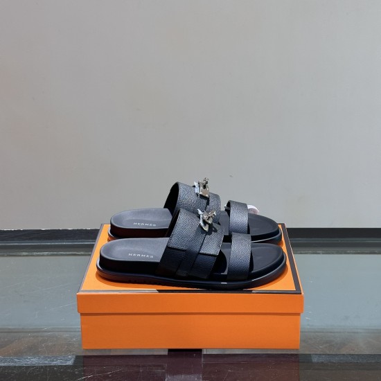 Hermes Jackson Leather Sandals In Black - Paired View in black and silver Pair of Hermes Jackson Leather Sandals In Black resting on an orange designer box in black and silver