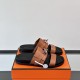 Hermes brown leather slide sandals on orange box in brown and silver Hermes brown leather slide sandals resting on an orange box in brown and silver